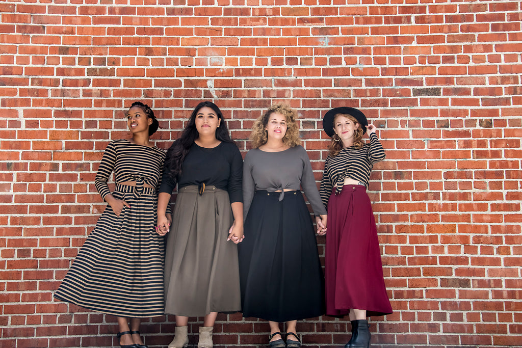 brick wall with women wearing tie tops and long skirts with pockets 