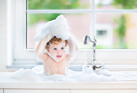 Baby spielt in der Badewanne mit Schaum
