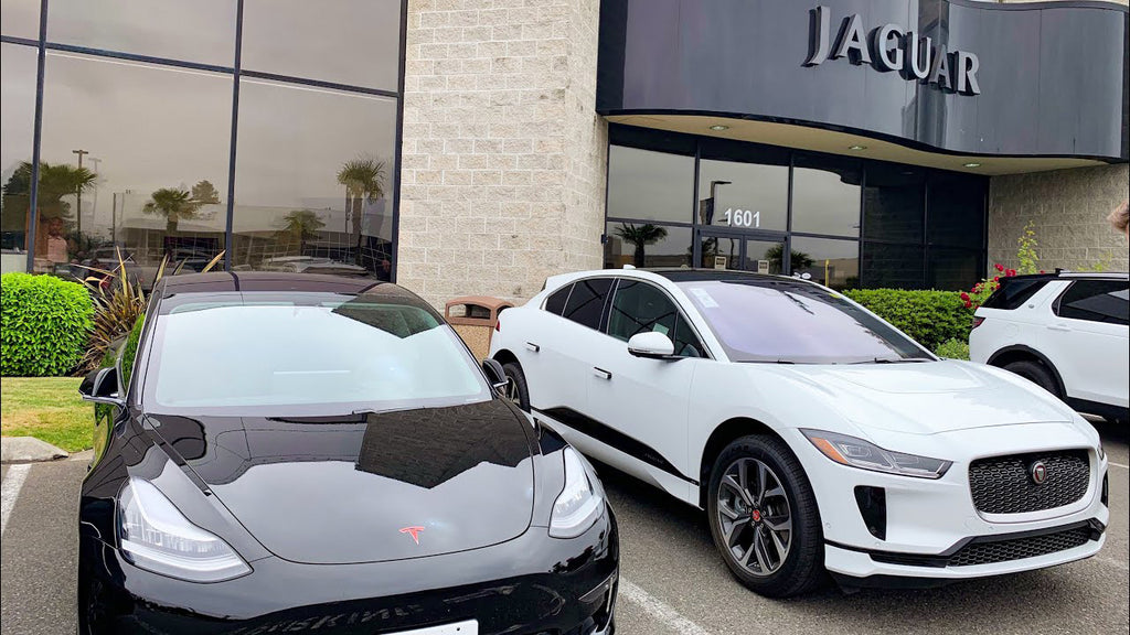 Tesla Model 3 and Jaguar i-Pace side by side outside a Jaguar dealdership.