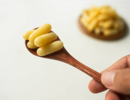 Spoon filled with honey alongside honey supplement tablets from the Honey Pot brand.