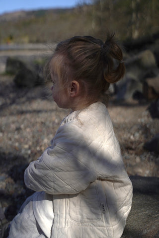 little law girl sitting with white padded jacket