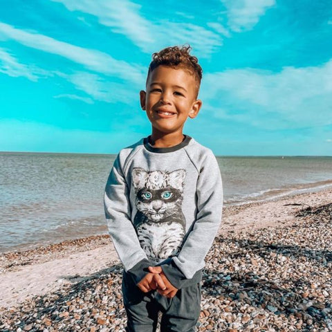 little boy wearing a recycled jumper by the sea