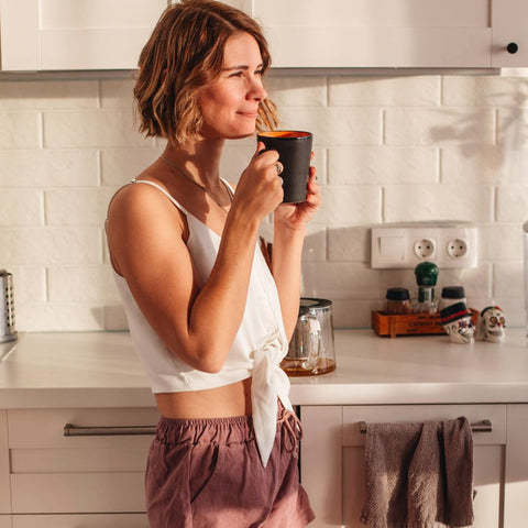 Person enjoying a mug of coffee in their kitchen