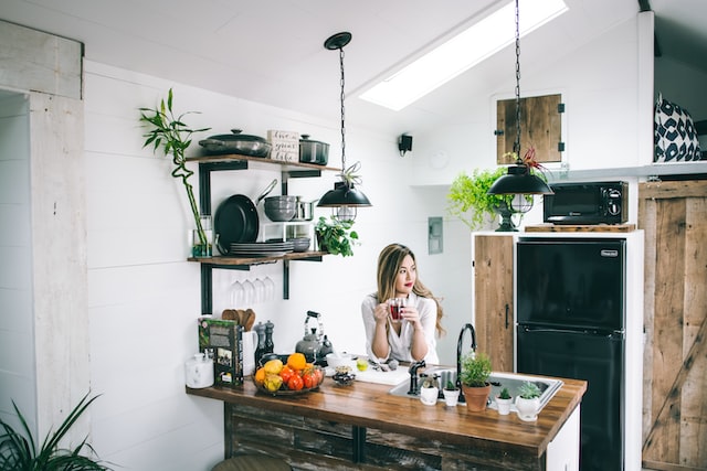 femme assise dans la cuisine avec des plantes et buvant un café