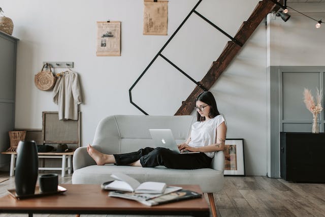 femme regardant un ordinateur assise sur un petit canapé