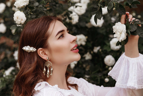 woman with ornate hair clip looking at flowers