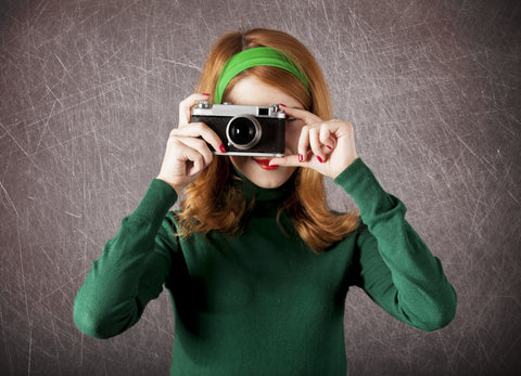 woman with retro flipped hair looking through an old camera