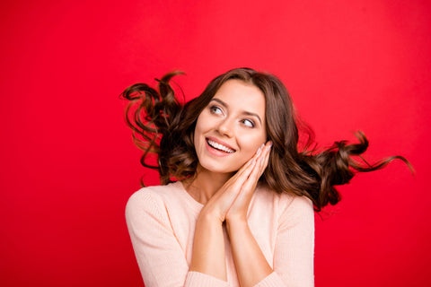 a woman holding her hands by her face on red background