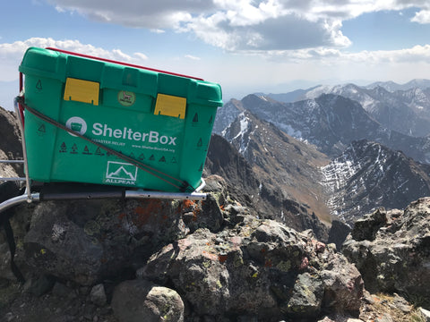 ShelterBox atop 14er with All Peak logo sticker