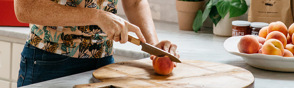 Person cutting a peach on a cutting board