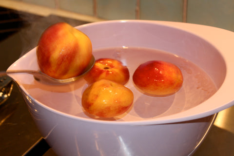 Peaches being scooped out of a bowl