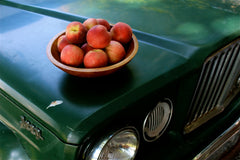 A bowl of peaches on the hood of an old truck