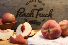 Sliced peaches in front of a The Peach Truck logo in wood