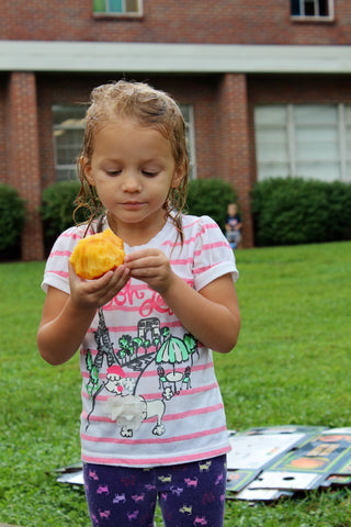 Little girl carefully eating a peach outside