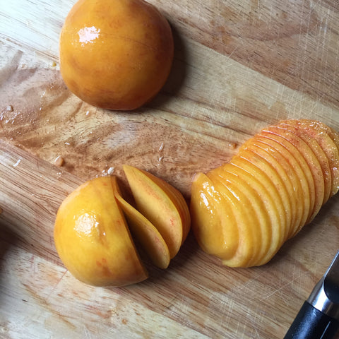 A peeled peach being sliced thinly