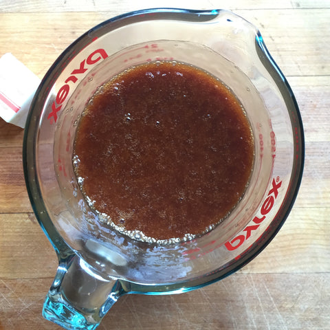 A measuring cup with the caramel bourbon topping inside