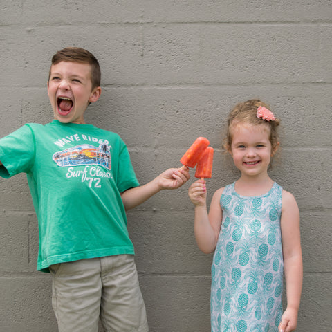 Two kids celebrating their peach lemonade popsicles