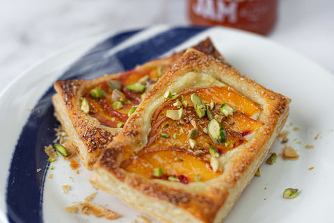 Two peach pistachio danishes on a white and blue plate