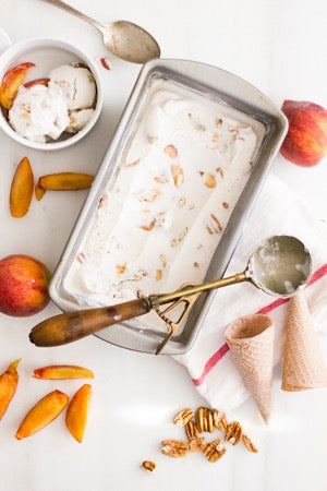 A batch of peach ice cream partially scooped out