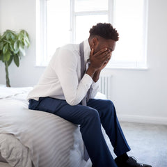 black man with his head in his hands looking stressed