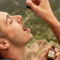 a man using a bottle dropper to put full spectrum hemp oil into his mouth