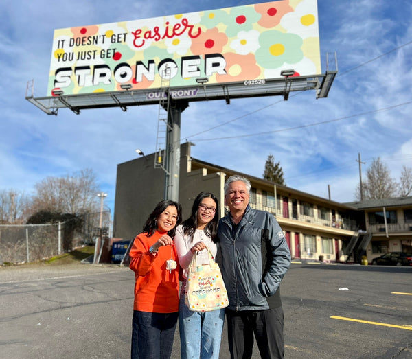 3 people standing in front of Maika's billboard in Portland