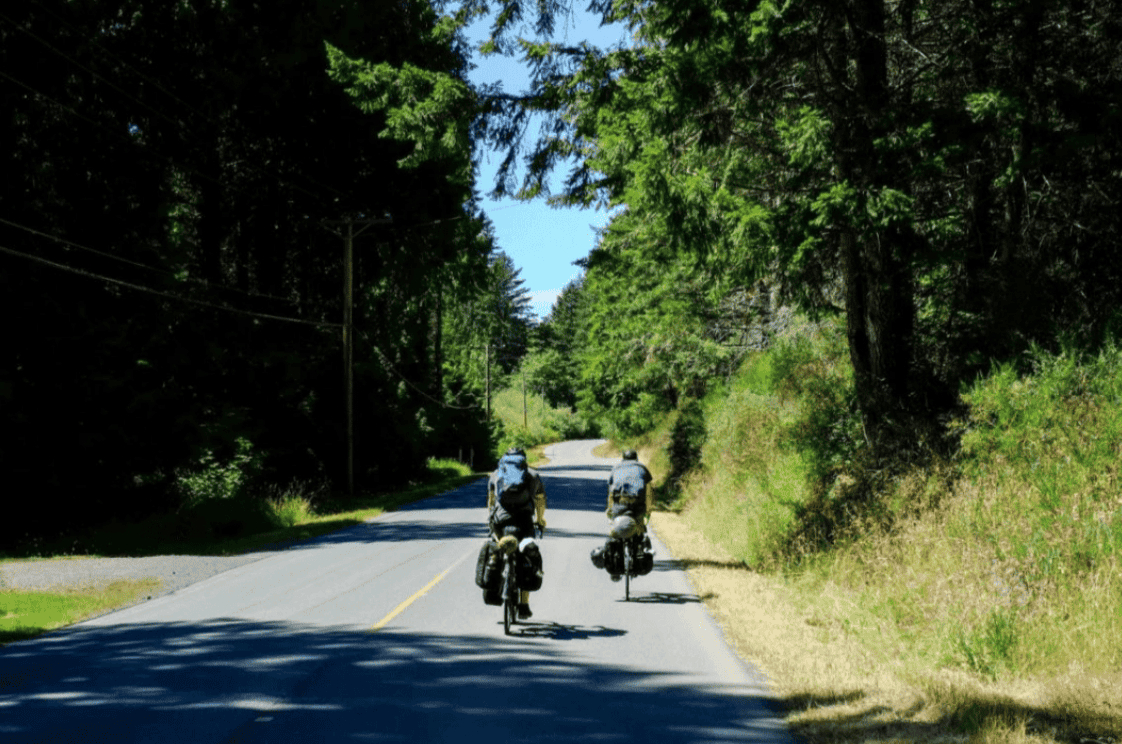 Two people bike-touring on a rural road.