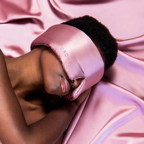 Model sleeping with a Drowsy pink silk sleep mask covering her eyes