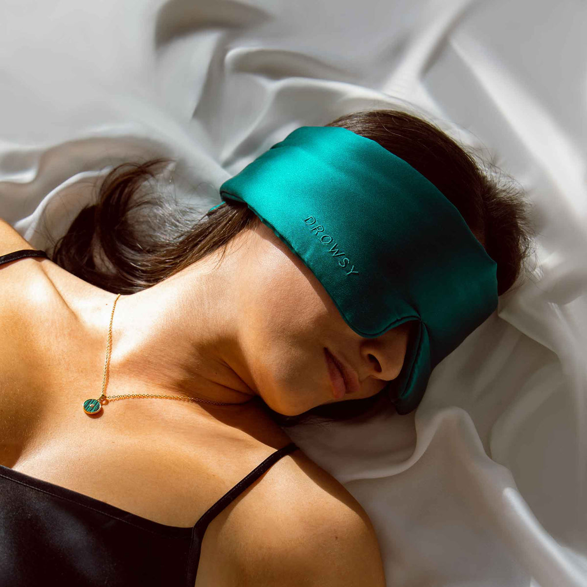 Model sleeping in bed with Drowsy Sleep Co. Green Sapphire mask covering her eyes