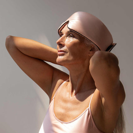 A Drowsy pink silk sleep mask on a models head