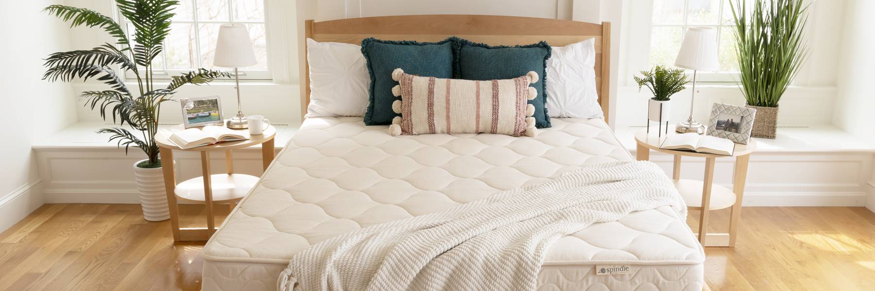 纺锤乳胶床垫与枕头揭开木床架与窗户的背景。