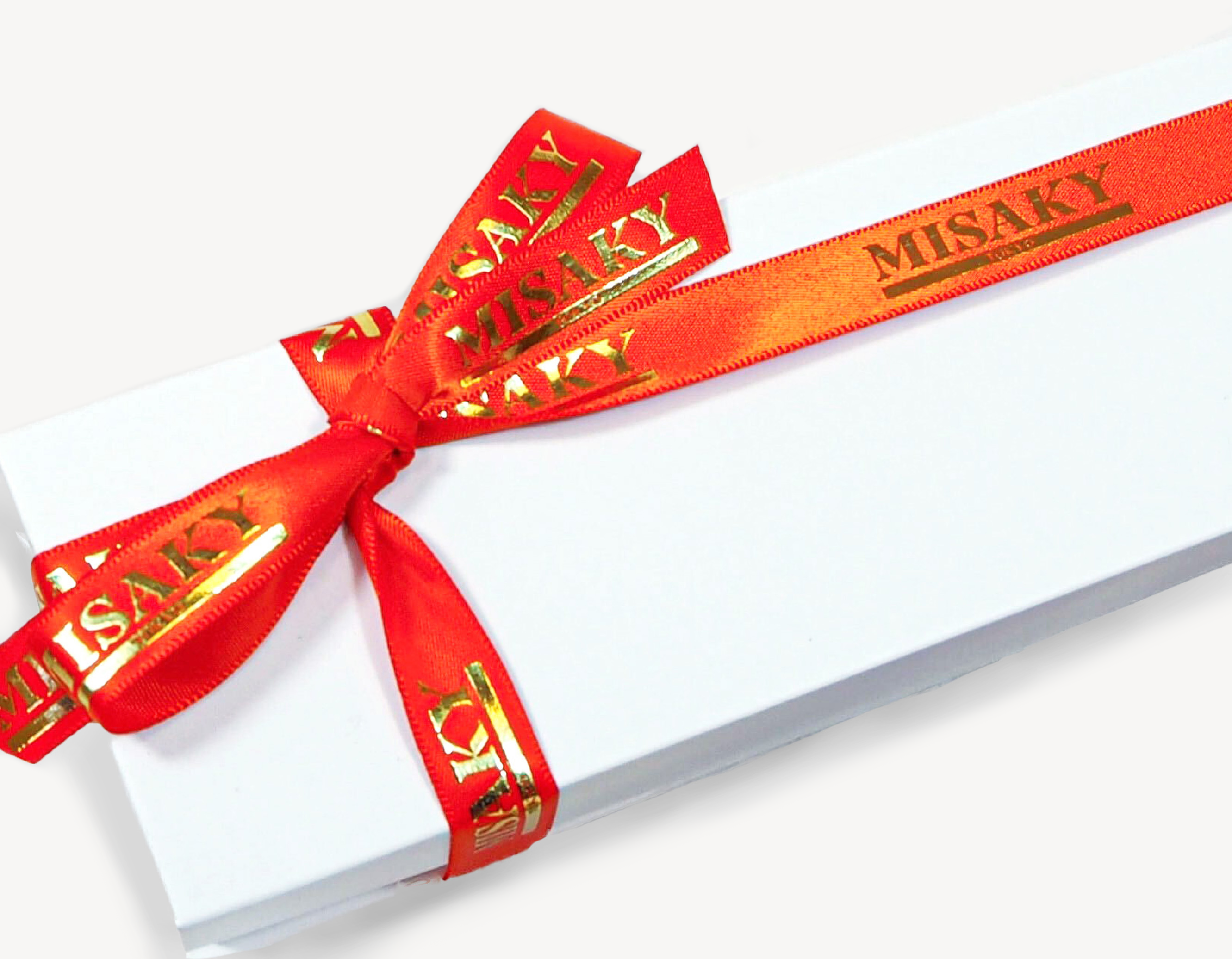 An elegant white gift box tied with a red ribbon that has the word 'MISAKI' printed in gold letters, presented on a white background