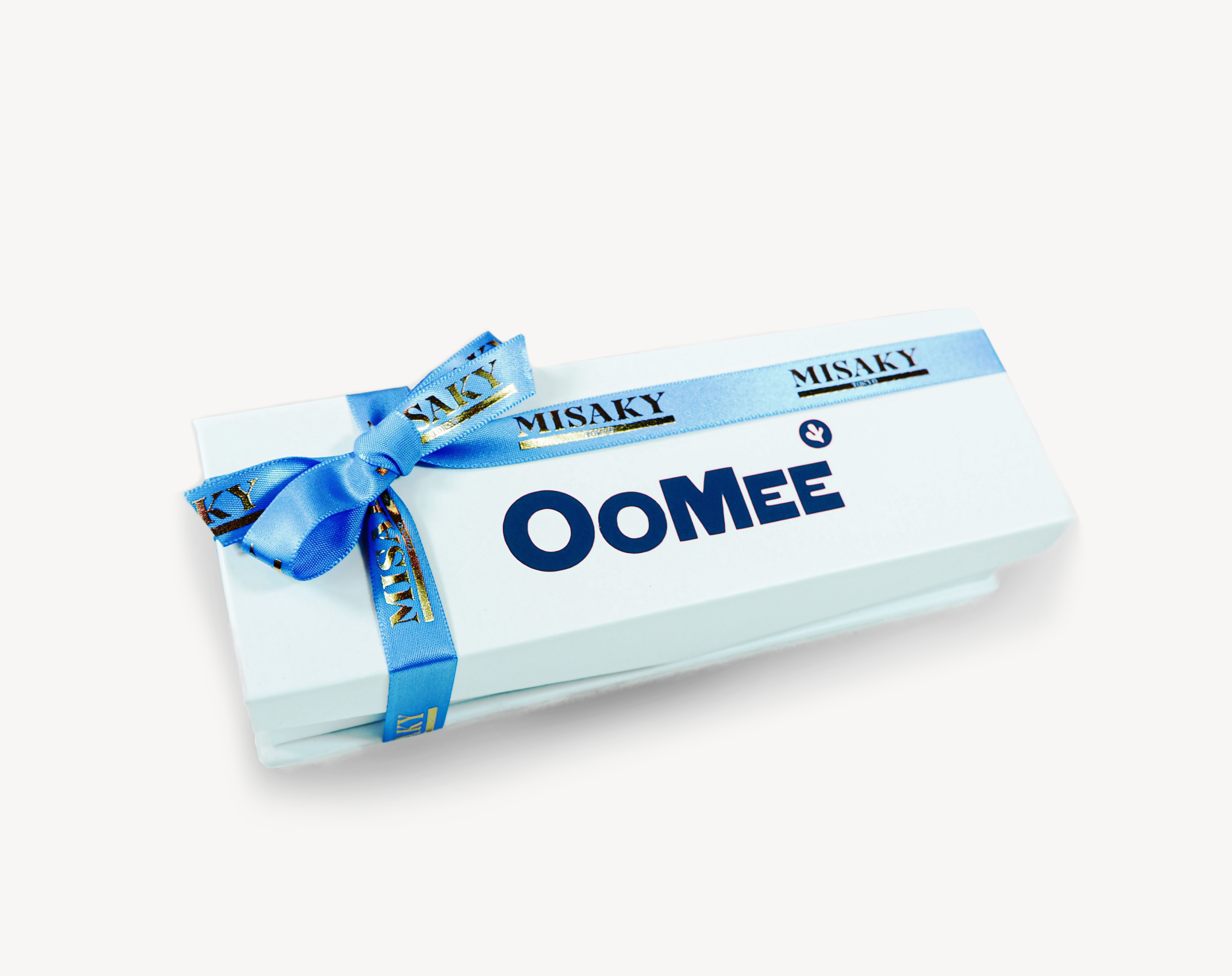 A white gift box with the word 'OOMEE' in large blue letters, tied with a blue satin ribbon printed with 'MISAKY' in gold, set against a white background.