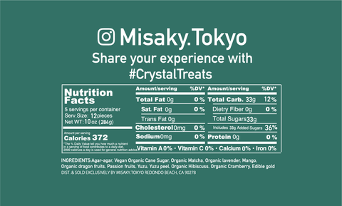 The image is a nutritional facts label for a product from Misaky.Tokyo, inviting customers to share their experience with the hashtag #CrystalTreats. It details that the serving size is 2 pieces (28g), and there are 5 servings per container. Each serving contains 372 calories and provides 0g of total fat, saturated fat, trans fat, cholesterol, sodium, and protein, which all account for 0% of the daily value (DV). The total carbohydrate content is 93g per serving, which is 33% of the DV, including 0g of dietary fiber and 33g of total sugars (with 33g added sugars), making up 36% of the DV.  The ingredients listed are organic dragon fruit, passion fruit, yuzu, vegan organic hibiscus, organic cranberry, and edible gold.  The product is distributed and sold exclusively by Misaky.Tokyo, with an address provided at the bottom of the label: 2617 Manhattan Beach Blvd, Redondo Beach, CA 90278.