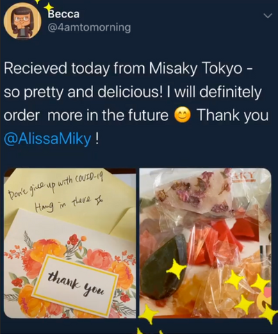 The image displays a social media post with two photographs. The post is from a user named Becca (@4amtomorning) and reads:  "Received today from Misaky Tokyo - so pretty and delicious! I will definitely order more in the future 😊 Thank you @AlissaMiky !"  The first photograph shows a handwritten note with floral borders that says "thank you" and a personal message that reads "Don't give up with COVID-19 Hang in there x". The second photograph displays an assortment of colorful, translucent candy in various shapes, suggesting that these are the products from Misaky Tokyo that Becca is praising for their beauty and taste. There are also some star-shaped confetti scattered among the candies, adding to the visual appeal of the presentation.