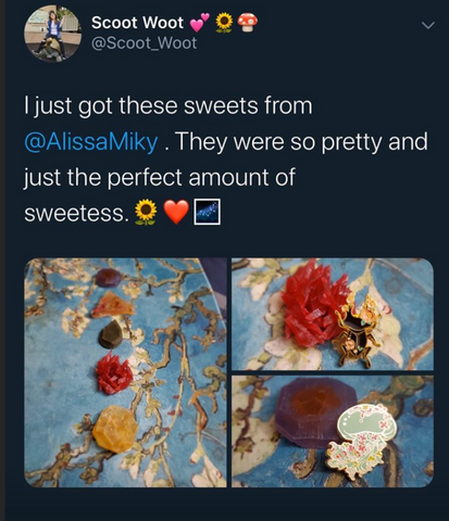 The image shows a tweet by a user named Scoot Woot (@Scoot_Woot) which includes text and four photographs of sweets. The tweet reads:  "I just got these sweets from @AlissaMiky. They were so pretty and just the perfect amount of sweetness. 🌞❤️🍫"  The accompanying photographs display a collection of artisanal Japanese-style candies on a marbled blue background. The candies are in various shapes and colors, some are clear and jewel-like, while others have floral and leaf inclusions, indicating a delicate and intricate crafting process. One of the candies has a small, decorative fan placed on it, adding to the aesthetic presentation. The arrangement and photography of the sweets suggest an appreciation for both their visual and gustatory qualities.