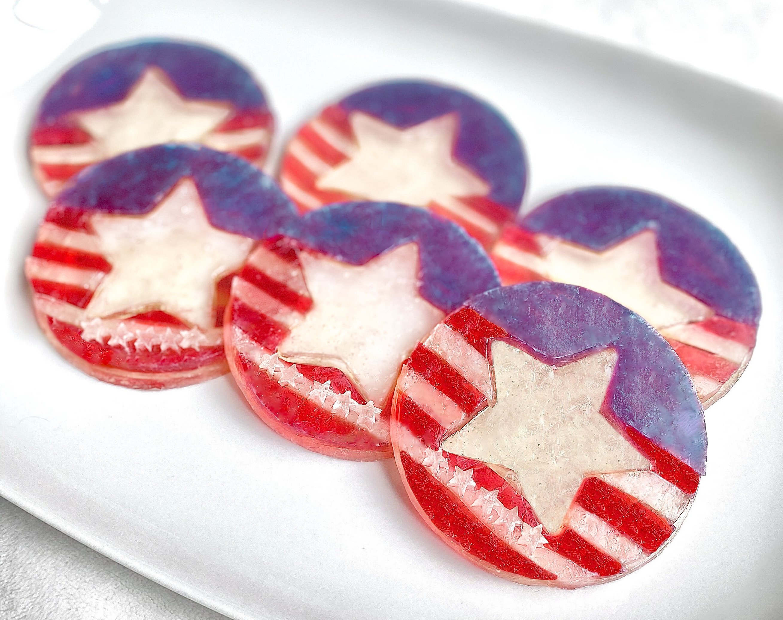 Sweets designed with an American flag motif, featuring a blue field with white stars and alternating red and white stripes, presented on a white plate or surface.