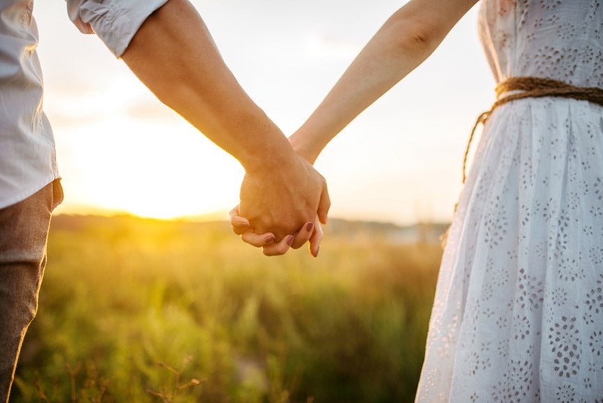 couple hold hands in a green field