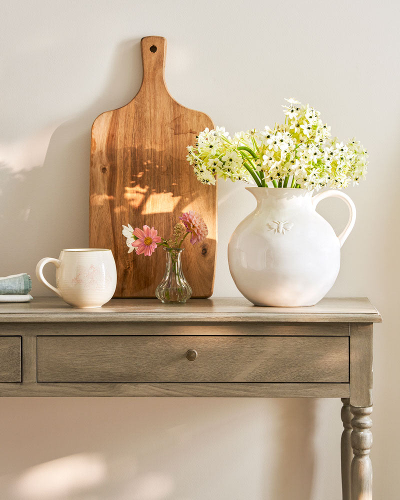 White stoneware just with Sophie Allport's bee motif filled with dainty flowers on a side table