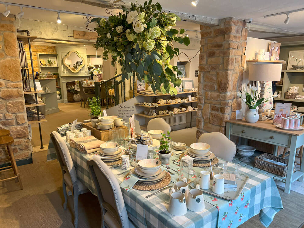 Sophie Allport Stamford Shop Tablescape featuring Gingham table linen, placemats, bowls, bowls trays and fine bone china scattered across a country dining table