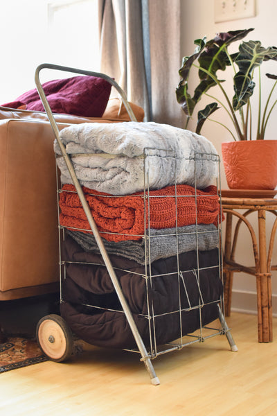 a stack of folded blankets in a repurposed vintage cart