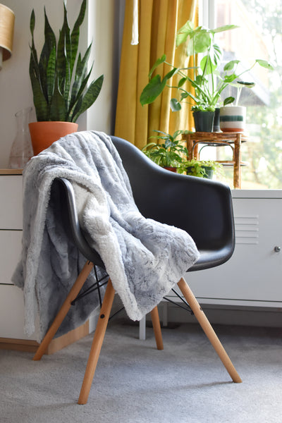 grey blanket draped over back, seat, and arm of chair
