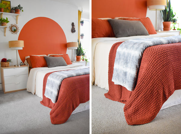 grey blanket folded and placed at foot of bed and layered over folded orange blanket