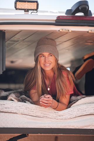 a woman lays on a mattress topper in her van