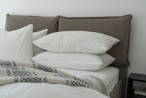 A photo of a bed with four fluffy white pillows