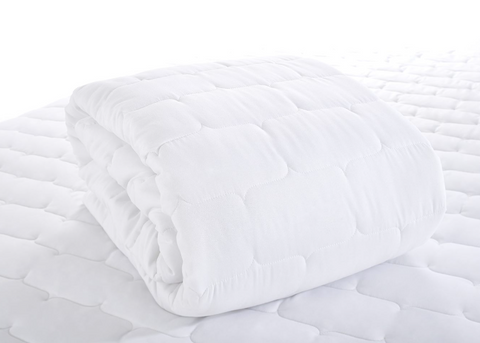 Photo of a white quilted mattress protector folded up and sitting on a bed