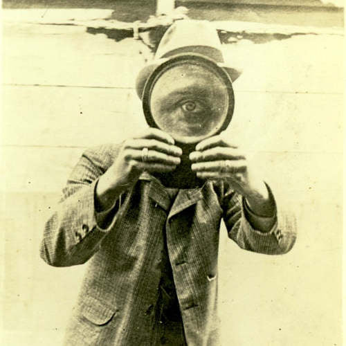 Man holding magnifying glass in front of eye