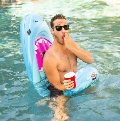 man sitting on a shark saddle seat pool float