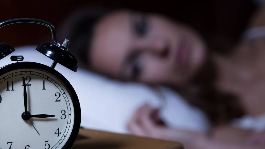 woman awake in bed with clock showing 3AM