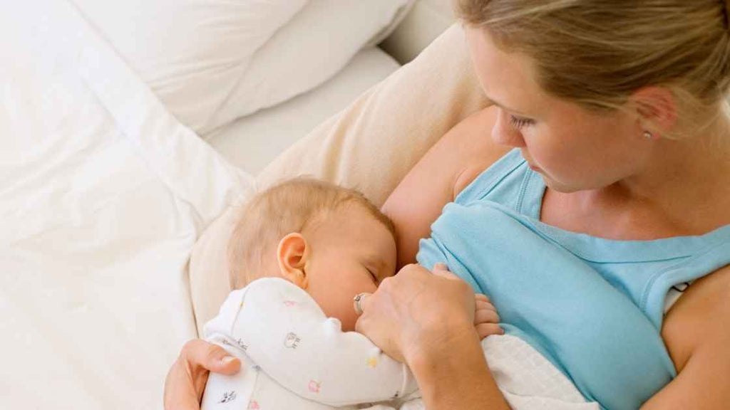 woman cuddling baby while breastfeeding